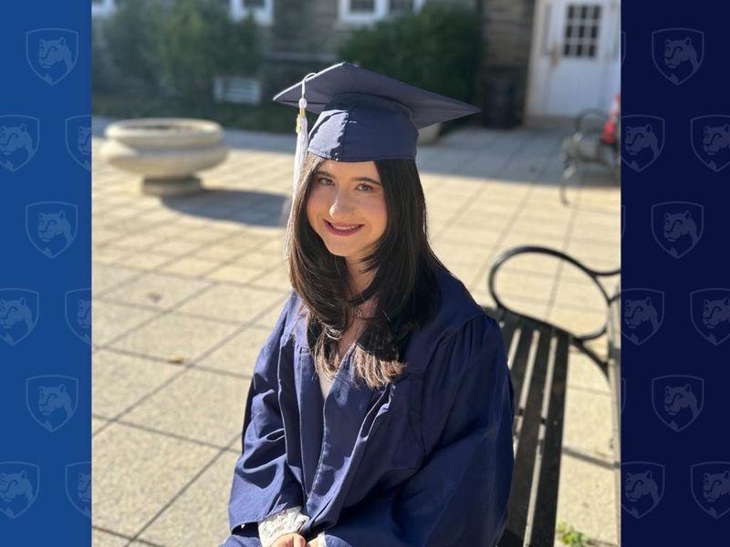 Student in cap and gown sitting outside